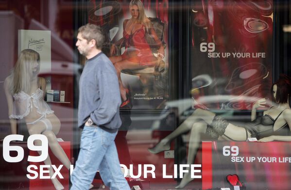 Мужчина идет мимо витрины, рекламирующей эротические товары в Берлине - Sputnik Молдова