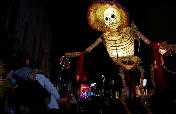 Прохожие смотрят на громадную светящуюся фигуру скелета во время фестиваля фонарей на празднике Хэллоуин в Ливерпуле, Великобритания - Sputnik Молдова