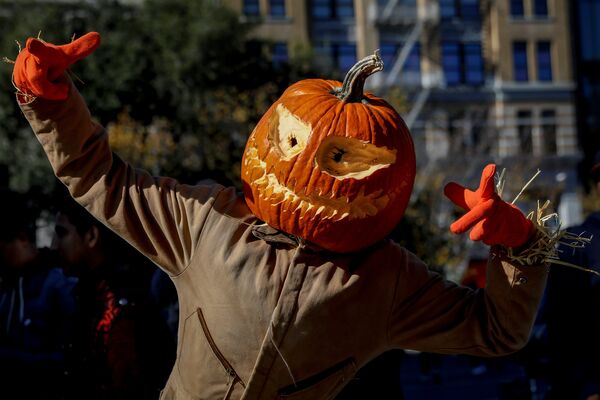 Человек в маскарадном костюме и с ужасающей тыквой на голове гуляет по центру Нью-Йорка во время празднования Хэллоуина - Sputnik Молдова