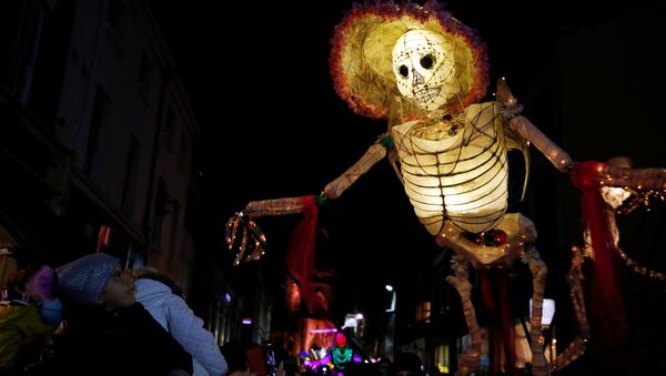 Прохожие смотрят на громадную светящуюся фигуру скелета во время фестиваля фонарей на празднике Хэллоуин в Ливерпуле, Великобритания - Sputnik Молдова