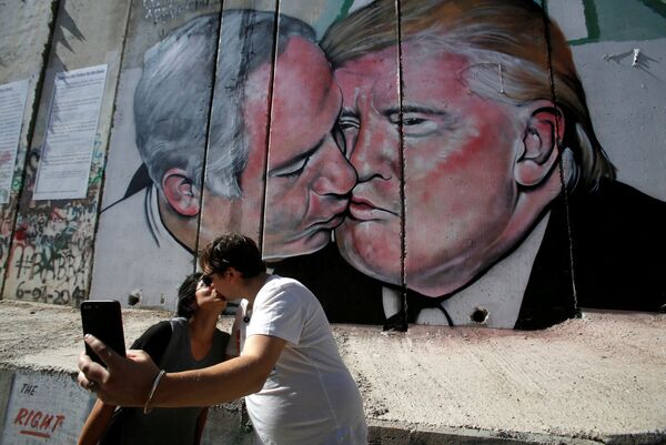 Туристы фотографируются у граффити с изображением поцелуя израильского премьер-министр Биньямина Нетаньяху и президента США Дональда Трампа на стене Вифлеема, Палестина - Sputnik Молдова