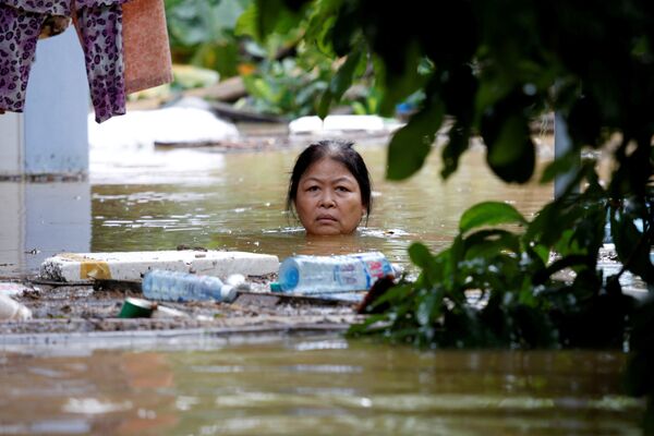 Провинции Вьетнама пострадали от наводнения. На фото - женщина пробирается через затопленную улицу после тайфуна Дамри - Sputnik Молдова