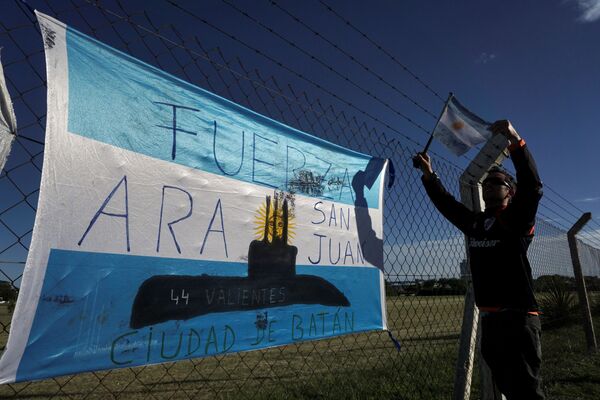 Мужчина развешивает аргентинский флаг у военно-морской базы Аргентины в Мар-дель-Плата во время поисков пропавшей подводной лодки Сан-Хуан - Sputnik Молдова