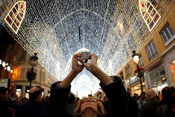 Женщина фотографирует рождественские гирлянды на улице Маркес де Лариос в Малаге, Испания - Sputnik Молдова