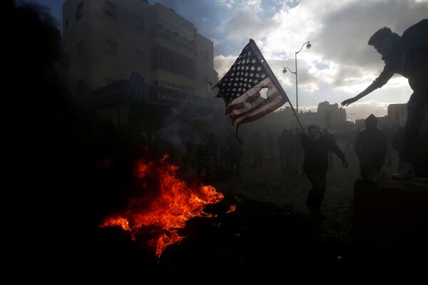 Палестинцы жгут американский флаг во время столкновений с израильской полицией в связи с протестами против решения Дональда Трампа признать Иерусалим столицей Израиля - Sputnik Молдова