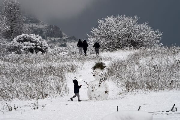 Ребенок рядом со снеговиком в окрестностях французского города Марсель - Sputnik Молдова