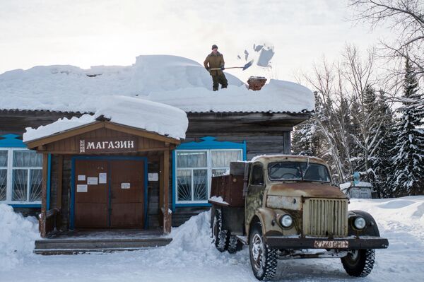 Мужчина чистит от снега крышу магазина в деревне Бобровка - Sputnik Молдова