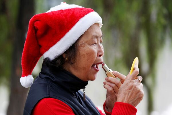Женщина в колпаке Санта-Клауса наносит макияж у озера Хоанкьем в Ханое, Вьетнам - Sputnik Молдова