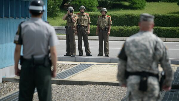 North Korean soldiers (C) take photos towards a South Korean soldier (L) and a US soldier (R) standing before the military demarcation line (lower C) seperating North and South Korea within the Joint Security Area (JSA) at Panmunjom on July 27, 2014 - Sputnik Moldova-România