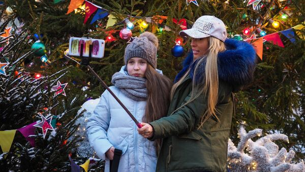 Taking selfies near the Christmas tree at the GUM-Fair on the Red Square in Moscow - Sputnik Молдова