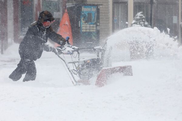 Un bărbat își croiește drum, cu ajutorul unui plug de zăpadă, pe una dintre străzile orașului Port Washington, New York, SUA - Sputnik Moldova