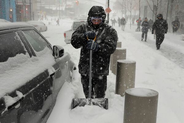 Человек пытается очистить свою машину от снега после снежной бури в Нью-Йорке, США - Sputnik Молдова