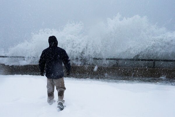 Человек смотрит на бушующий океан во время шторма Грейсон в Линне, пригород Бостона, штат Массачусетс, США - Sputnik Молдова