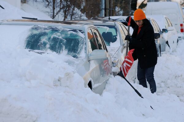 Женщина очищает свою машину от снега после шторма Грейсон в Бостоне, штат Массачусетс, США - Sputnik Молдова