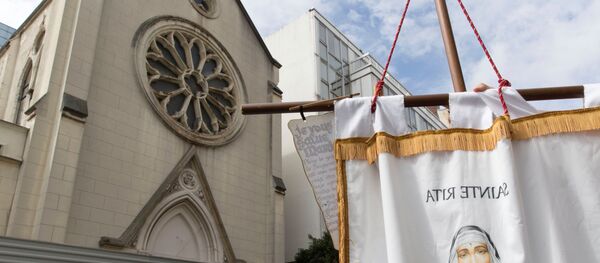 A person holds a banner picturing Sainte-Rita as other stand in front of barriers blocking the access to the sainte-Rita church in Paris with an inscription on it which translates as In France, priests are killed and churchs are demolished, on August 3, 2016 - Sputnik Moldova