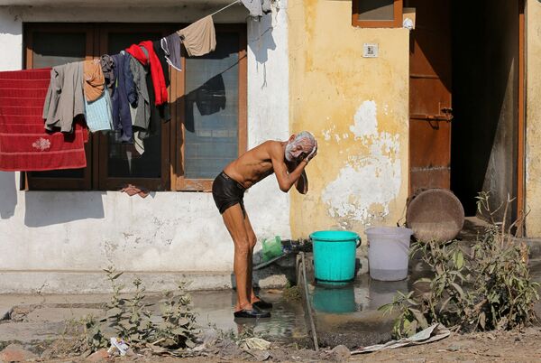 Un bărbat, spălându-se din găleată, într-o piață din orașul indian Jammu - Sputnik Moldova