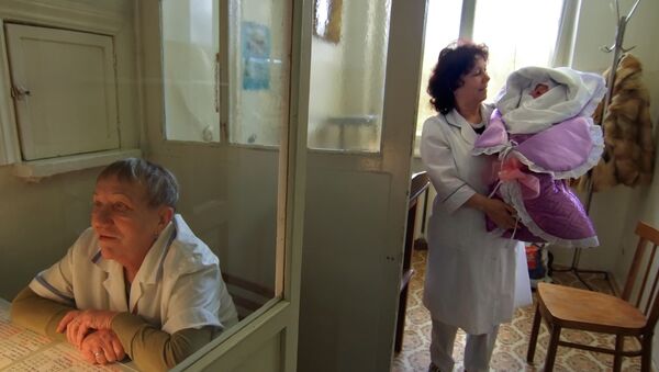 Акушерка выносит новорожденного во время выписки из роддома - Sputnik Moldova-România