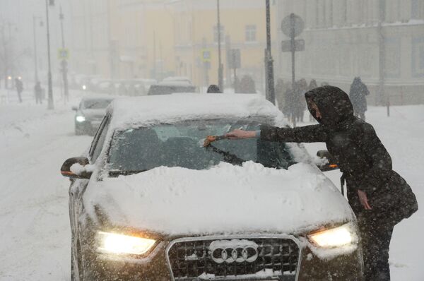 Владелица отчищает свою машину от налипшего снега во время снегопада в Москве - Sputnik Молдова
