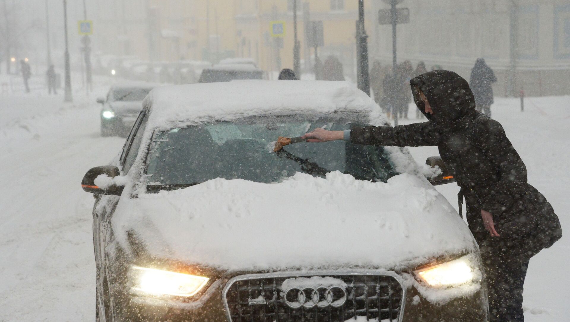 Владелица отчищает свою машину от налипшего снега во время снегопада в Москве - Sputnik Moldova-România, 1920, 17.02.2021