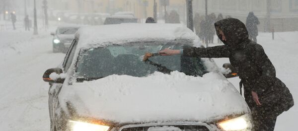 Владелица отчищает свою машину от налипшего снега во время снегопада в Москве - Sputnik Молдова