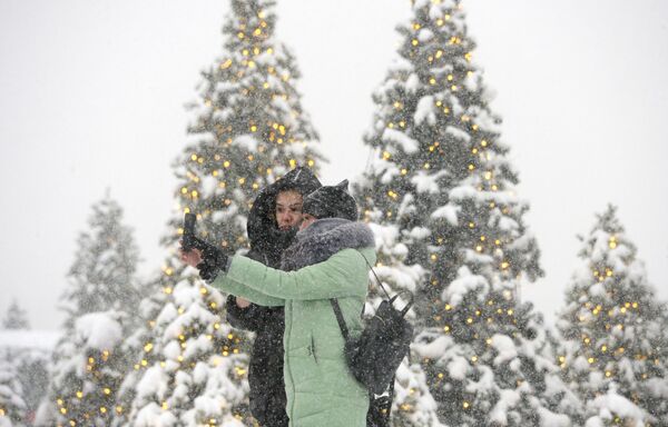 Девушки фотографируются во время снегопада на Манежной площади в Москве - Sputnik Молдова