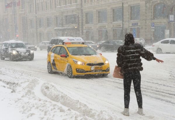 Девушка ловит такси на Тверской улице во время снегопада - Sputnik Молдова