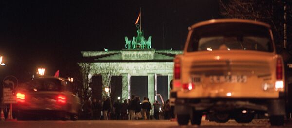 East German cars, in particular a Trabant (R), also know as the Trabi, or as the cardboard-box-on-wheels, the car which symbolised communist East Germany, wait at Unter den Linden avenue in East Berlin the opening of the crossing point under the Brandenburg Gate (background) into West Berlin after the opening of the Berlin Wall on November 09, 1989. - Sputnik Moldova-România