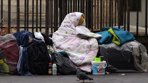 A homeless woman is wrapped in a blanket on the sidewalk of a Parisian street - Sputnik Moldova