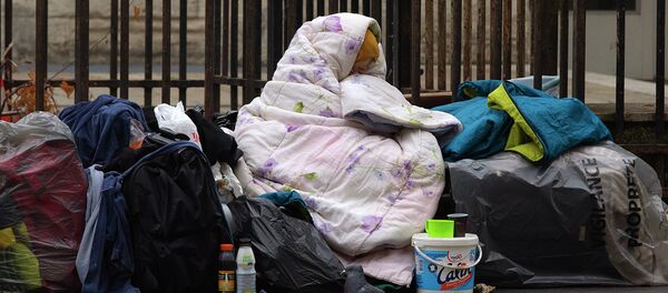 A homeless woman is wrapped in a blanket on the sidewalk of a Parisian street - Sputnik Moldova