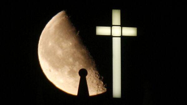 A third quarter Buck Moon rises behind a spire on the top of the bell tower next to a lighted cross - Sputnik Moldova-România