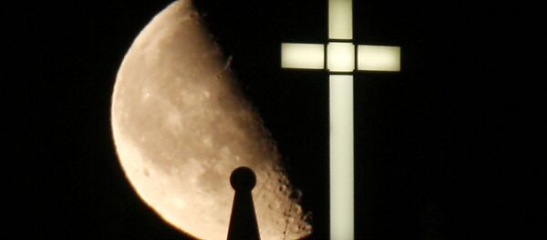 A third quarter Buck Moon rises behind a spire on the top of the bell tower next to a lighted cross - Sputnik Moldova-România