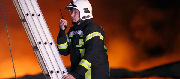 Сотрудник противопожарной службы во время тушения пожара Сотрудник противопожарной службы во время тушения пожара - Sputnik Молдова