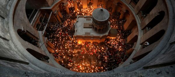 Верующие со свечами во время сошествия благодатного огня в Храм Гроба Господня в Иерусалиме - Sputnik Moldova