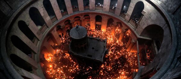 Christian Orthodox worshipers hold up candles lit from the Holy Fire as thousands gather in the Church of the Holy Sepulchre in Jerusalem’s Old City - Sputnik Moldova-România