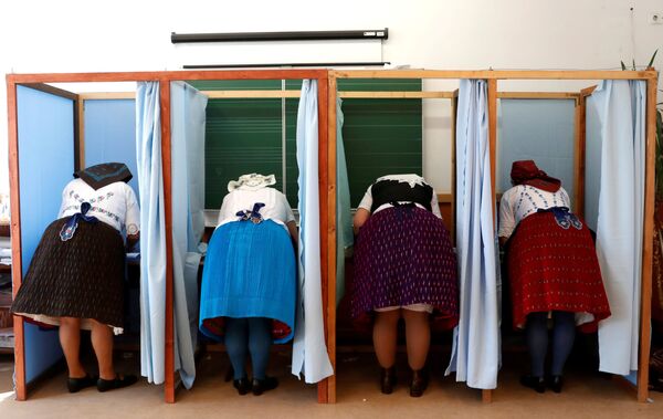 Венгерские женщины в традиционных костюмах заполняют избирательные бюллетени на избирательном участке во время венгерских парламентских выборов, Венгрия - Sputnik Молдова