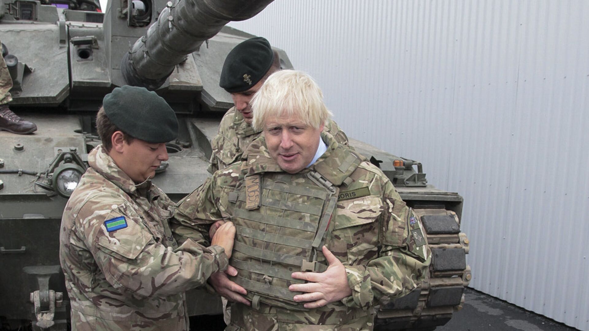 British Foreign Secretary Boris Johnson, right, has a flack jacket adjusted by an unidentified serviceman while visiting a NATO military unit outside Tallinn, Estoni - Sputnik Moldova-România, 1920, 28.12.2021