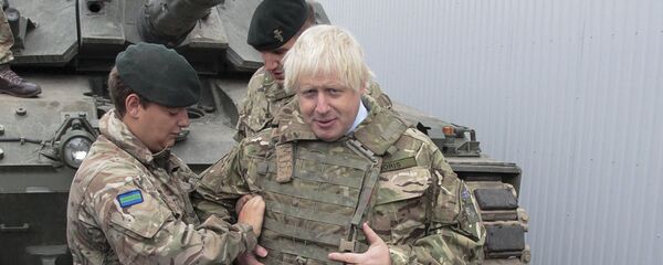 British Foreign Secretary Boris Johnson, right, has a flack jacket adjusted by an unidentified serviceman while visiting a NATO military unit outside Tallinn, Estoni - Sputnik Moldova-România
