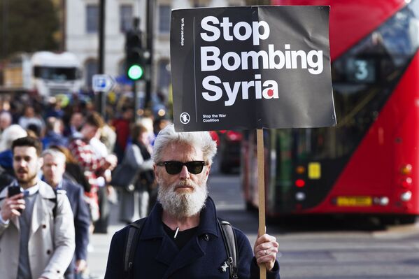 Мужчина держит плакат, призывающей не бомбить Сирию, на акции протеста против ударов по Сирии в Лондоне - Sputnik Молдова