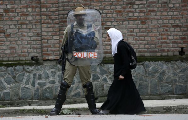 Мусульманская студентка идет мимо индийского полицейского во время протеста против недавних случаев изнасилования в городе Сринагар в Кашмире, Индия - Sputnik Молдова