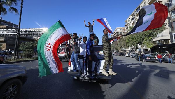 Syrian government supporters wave Syrian, Iranian and Russian flags as they chant slogans against U.S. President Trump during demonstrations following a wave of U.S., British and French military strikes to punish President Bashar Assad for suspected chemical attack against civilians, in Damascus, Syria, Saturday, April 14, 2018 - Sputnik Moldova-România