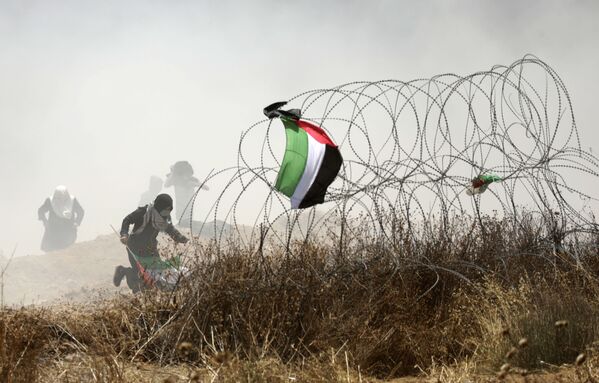 Палестинский демонстрант во время столкновений с израильскими силами у границы между сектором Газа и Израилем - Sputnik Moldova-România
