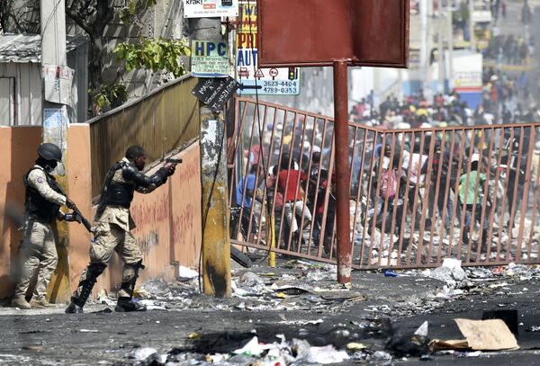 Полицейский направляет пистолет на людей, чтобы избежать мародерства во время протестов против повышения цен на топливо близ столицы Гаити - Sputnik Молдова