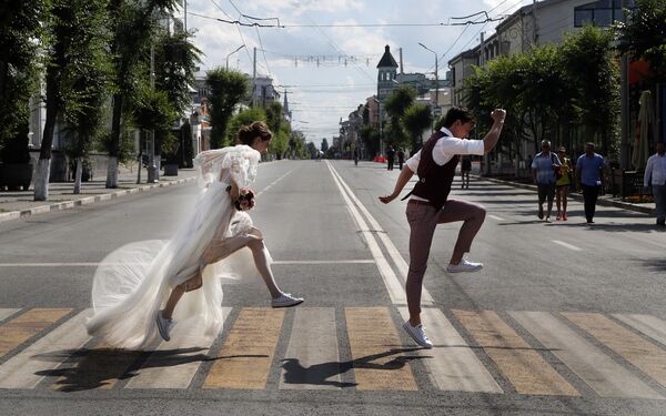 Молодожены позируют свадебному фотографу на дорожной зебре во время ЧМ-2018 в Самаре, Россия - Sputnik Молдова