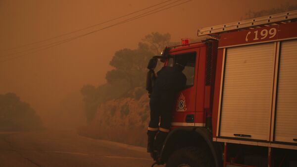A fire truck is engulfed in a pall of orange smoke on a road near Kineta, west of Athens, Monday, July 23, 2018. - Sputnik Moldova-România