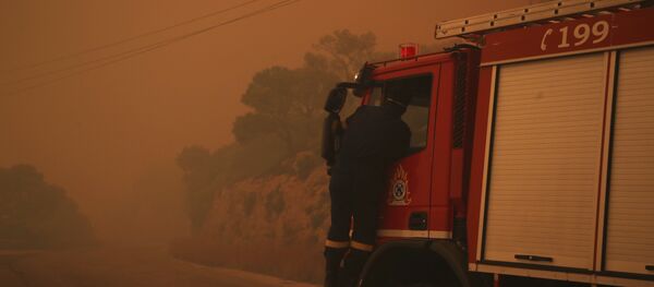 A fire truck is engulfed in a pall of orange smoke on a road near Kineta, west of Athens, Monday, July 23, 2018. - Sputnik Moldova