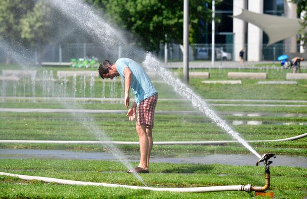 Мужчина охлаждается под брызгами воды в Берлине, Германия - Sputnik Молдова