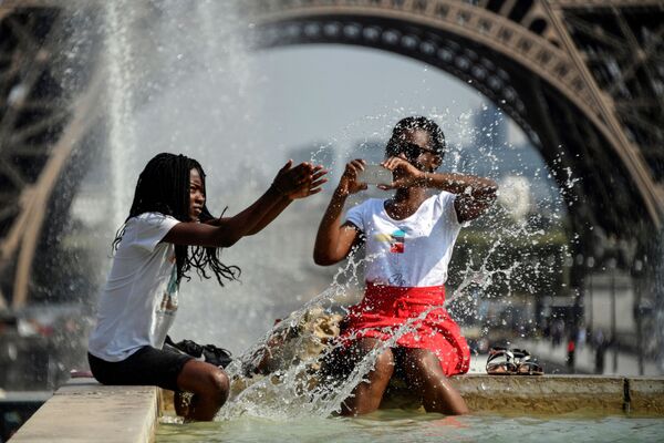 Девушки охлаждаются в фонтане напротив Эйфелевой башни во время жаркого дня в Париже - Sputnik Молдова