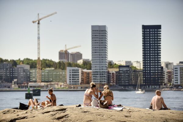 Горожане принимают солнечные ванны в жаркий летний день в центре Стокгольма - Sputnik Молдова