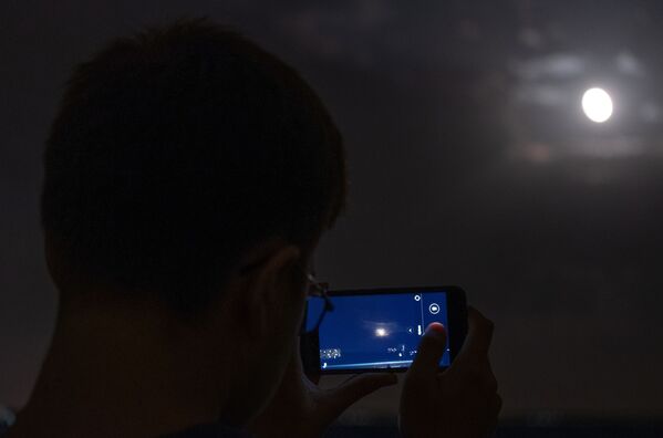 Мужчина снимает на телефон луну во время полного затмения из обсерватории Кубанского Государственного университета - Sputnik Молдова