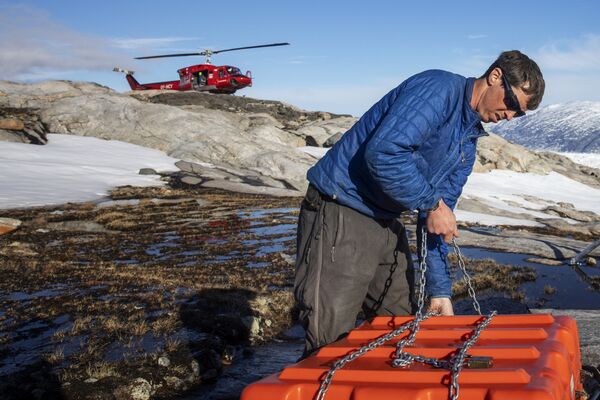 Сотрудник службы безопасности собирает оборудование для работы в научном лагере на леднике Хелхейм в Гренландии - Sputnik Молдова